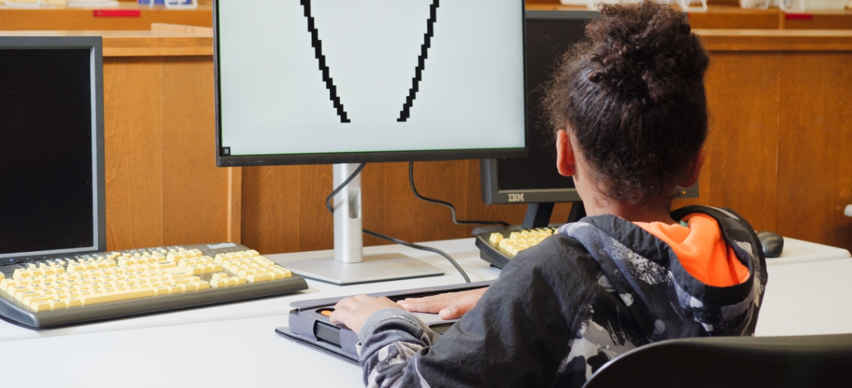 A student uses a Monarch to view a tactile graph while the graph is also being displayed on the computer screen in front of him.